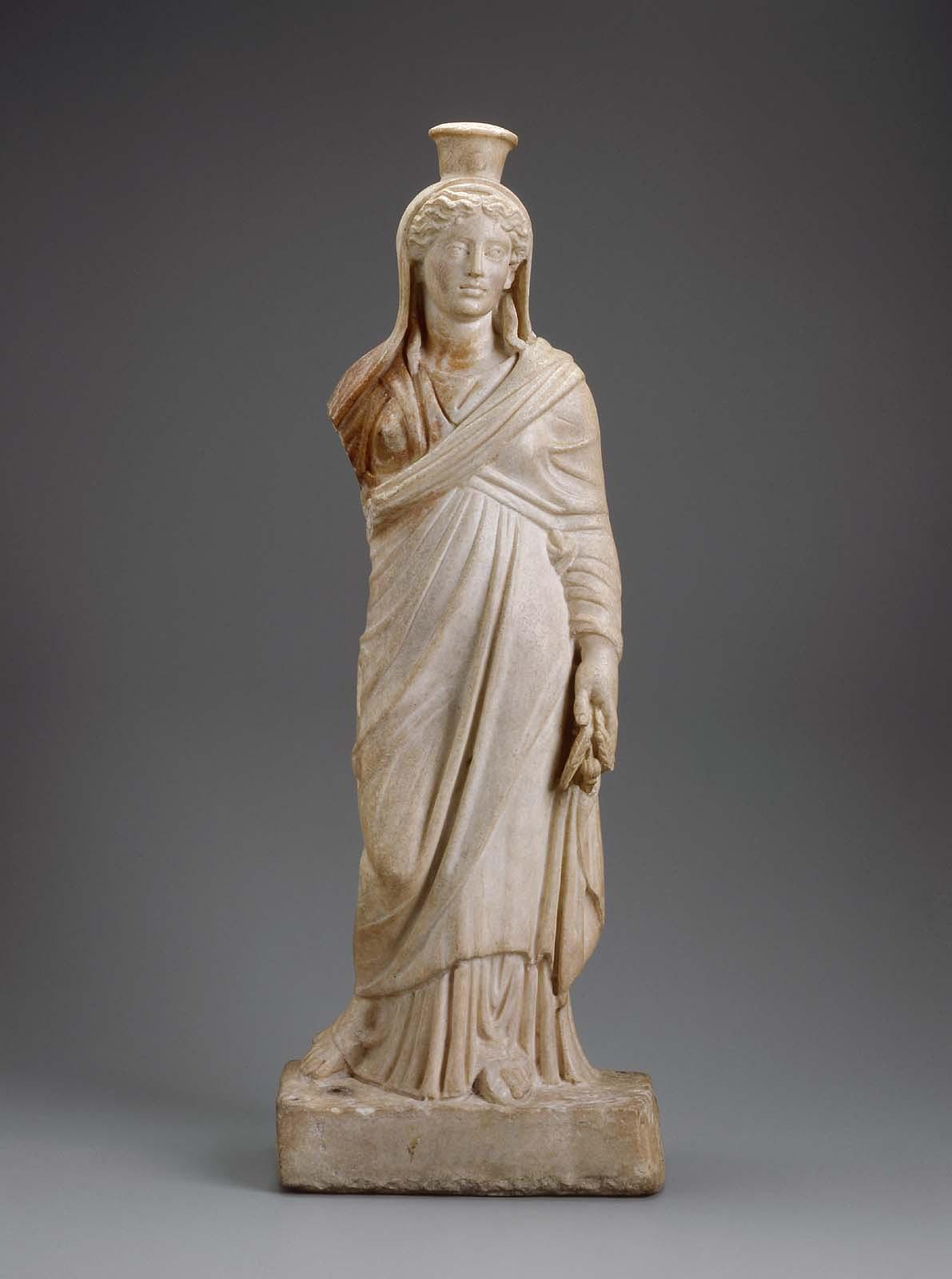 A marble statue of the goddess Demeter with small horns and a headdress with a sun disc.